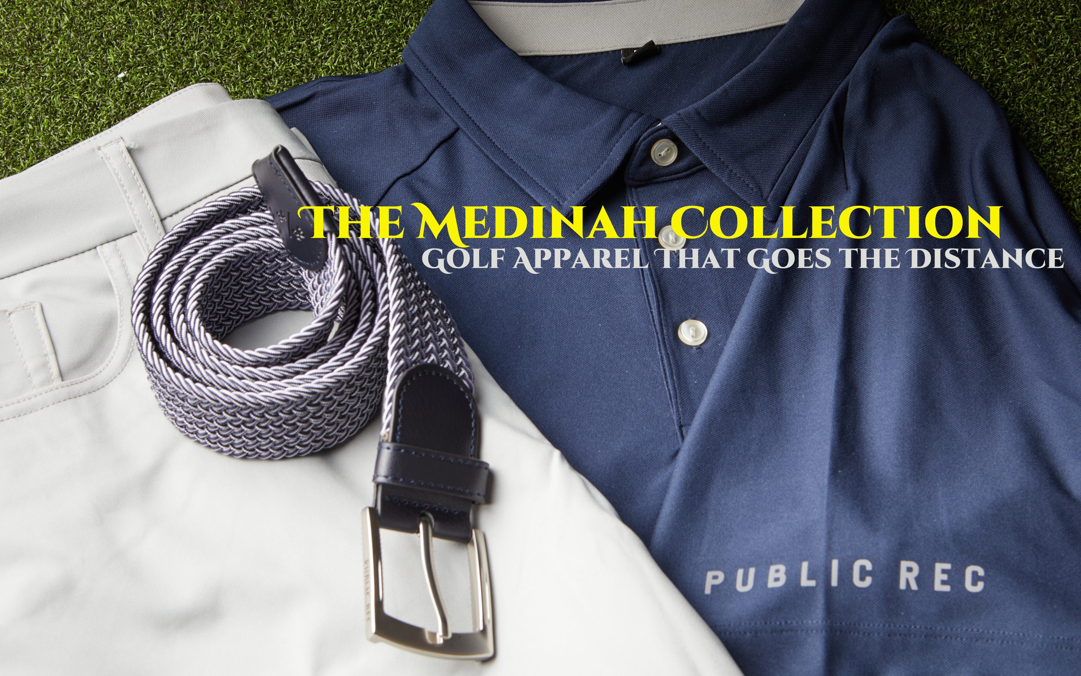 Public Rec Medinah Collection golf apparel - navy polo, woven belt and white pants laid out on turf